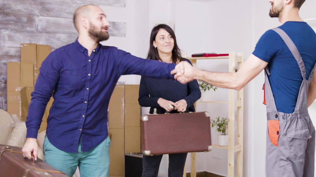 Coppia che saluta il traslocatore e riceve i bagagli nel nuovo appartamento