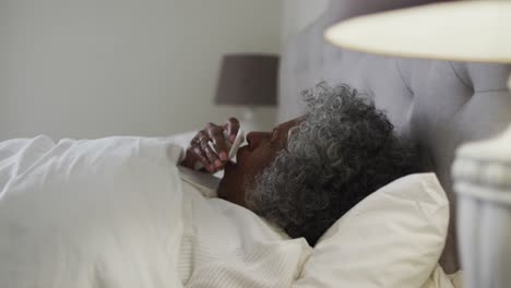 Kranke-ältere-Afroamerikanische-Frau-Hustet,-Während-Sie-Zu-Hause-Auf-Dem-Bett-Liegt