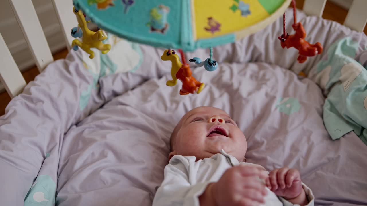 Bambino che si allunga verso la giostrina nella culla