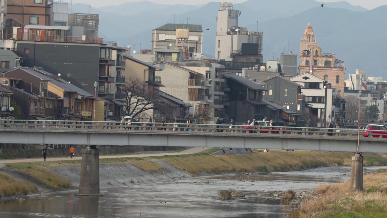 Kyoto'da Kamo Nehri üzerindeki köprüden geçen insanlar