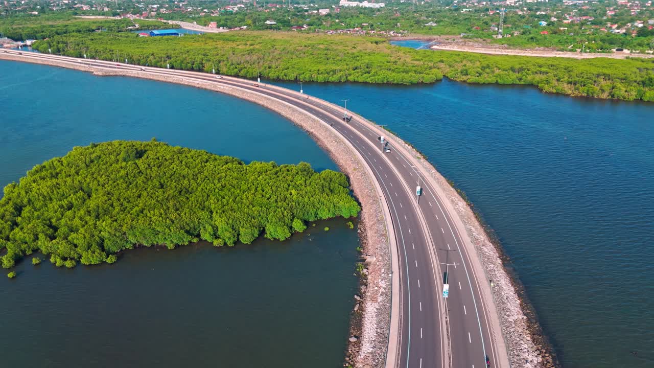 4K cinematic aerial drone footage of a curved coastal highway surrounded by clear blue ocean and lush mangrove forests in Cebu,Philippines.Ideal for tourism, environment, infrastructure,sustainability