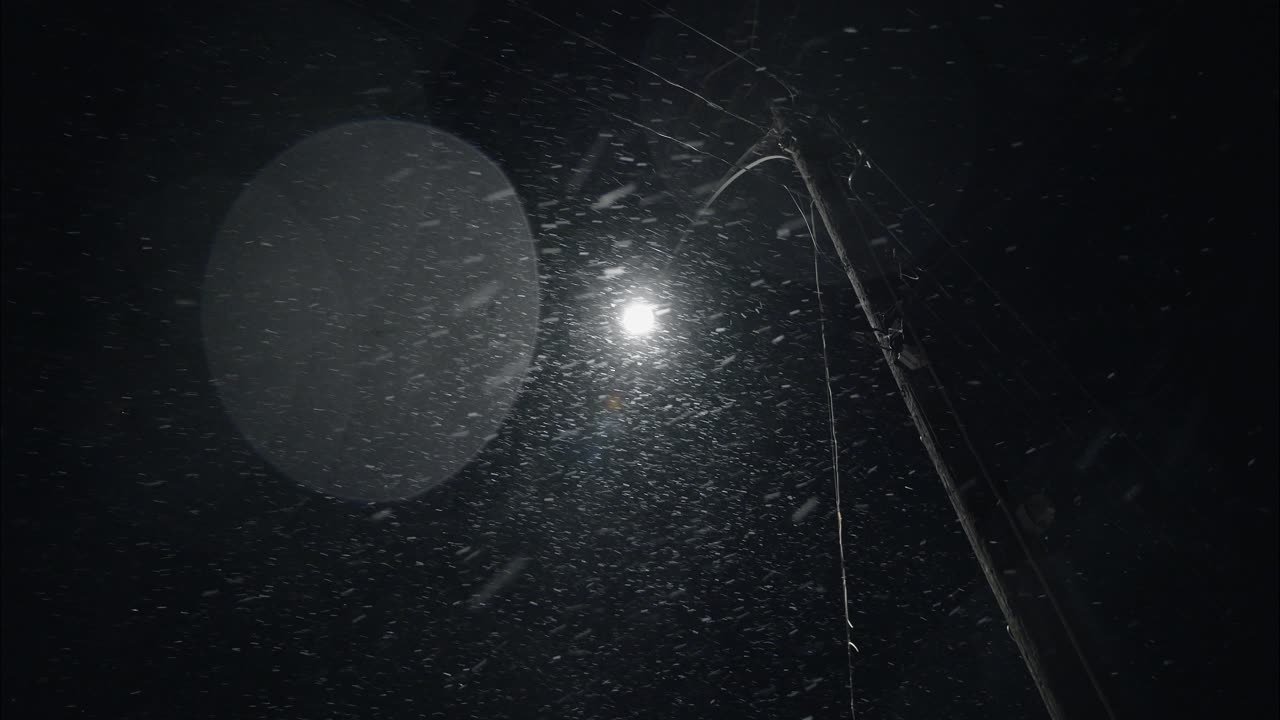 nevada de invierno por la noche nevando en la calle de la ciudad en la luz de la calle