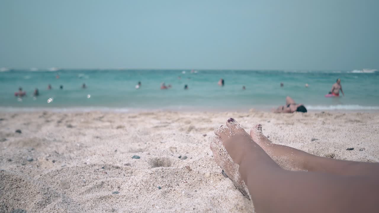 chica bañándose en la brillante luz del sol acostada en una playa de arena cálida