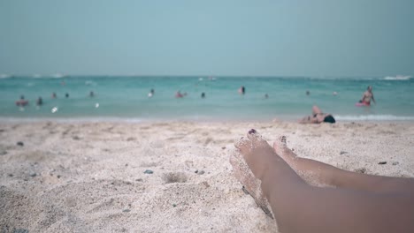 girl bathes in bright sunlight lying on warm sand beach