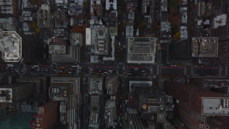 Aerial-birds-eye-overhead-top-down-panning-shot-of-busy-streets-in-between-tall-skyscrapers.-Slowly-moving-vehicles-on-avenue.-Manhattan,-New-York-City,-USA