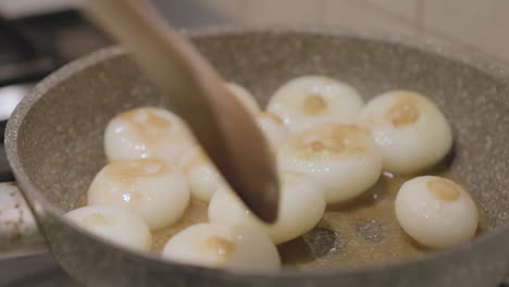 cooking onions on hot oilve oil in frying pan, close up slow motion