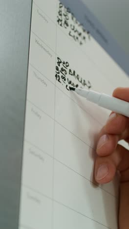 persona que escribe en un calendario de planificación semanal