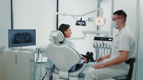 a male dentist communicates with a female patient in a dental office. dental health concept