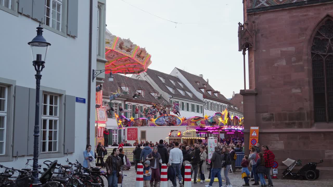 People at the Basel Autumn Fair 2024 on their way to Münsterplatz with chain carousel in the background