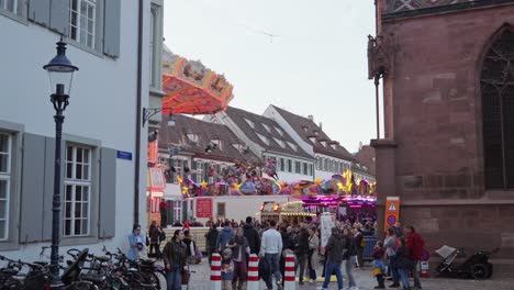 people at the basel autumn fair 2024 on their way to münsterplatz with chain carousel in the background