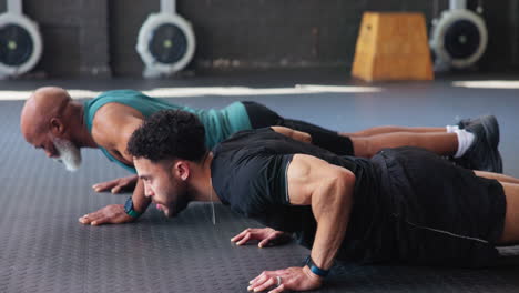 two men doing push-ups in a gym