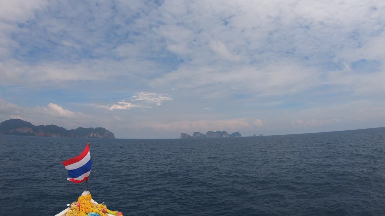 바람에 펄럭이는 태국 국기와 멀리 있는 피피섬, 4k 59의 태국과 함께 바다 위의 보트에서 볼 수 있습니다.