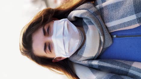 Beautiful-Caucasian-Female-Wearing-Medical-Mask-to-Protect-From-Covid19-Contamination-Young-Woman.Beautiful-Caucasian-female-wearing-medical-mask-to-protect-from-covid-19-contamination.-Young-woman-standing-on-street-and-looking-to-camera.-Virus,-pandemic,-safety-concept.