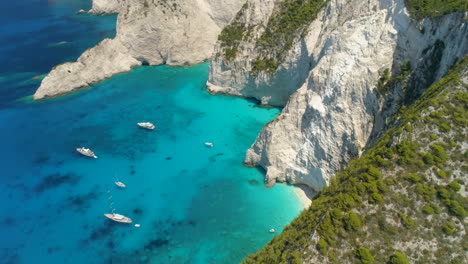 Aerial-Drone-Shot-of-a-tropical-Bay-with-some-Boats-and-big-Cliffs,-Zakynthos,-Greece,-4k-UHD