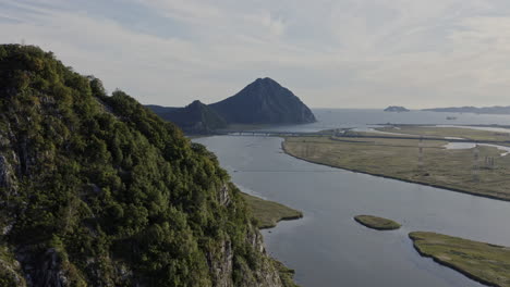 reveal of mountain ridge in the distance, with the river estuary passing through the valley, ships at anchorage in the bay during sunset time, aerial shot, russia