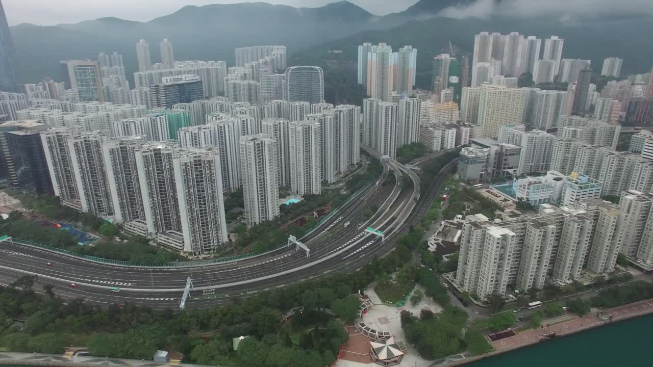 Aerial view of Hong Kong. Cityscape with high-rise buildings, lush green areas, and a winding highway. 4K.