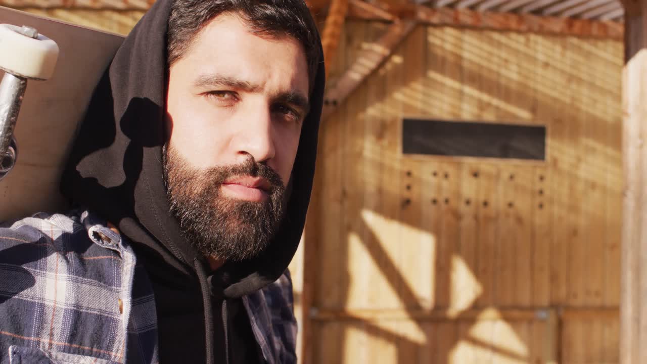 스케이트 파크에서 스케이트보드를 들고 있는 중동의 남성 스케이트보더의 중간 부분의 비디오