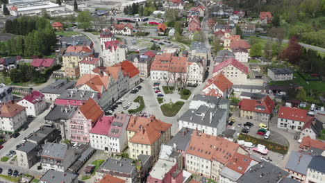 aerial orbit around market square in small european town with parking places and tenement houses