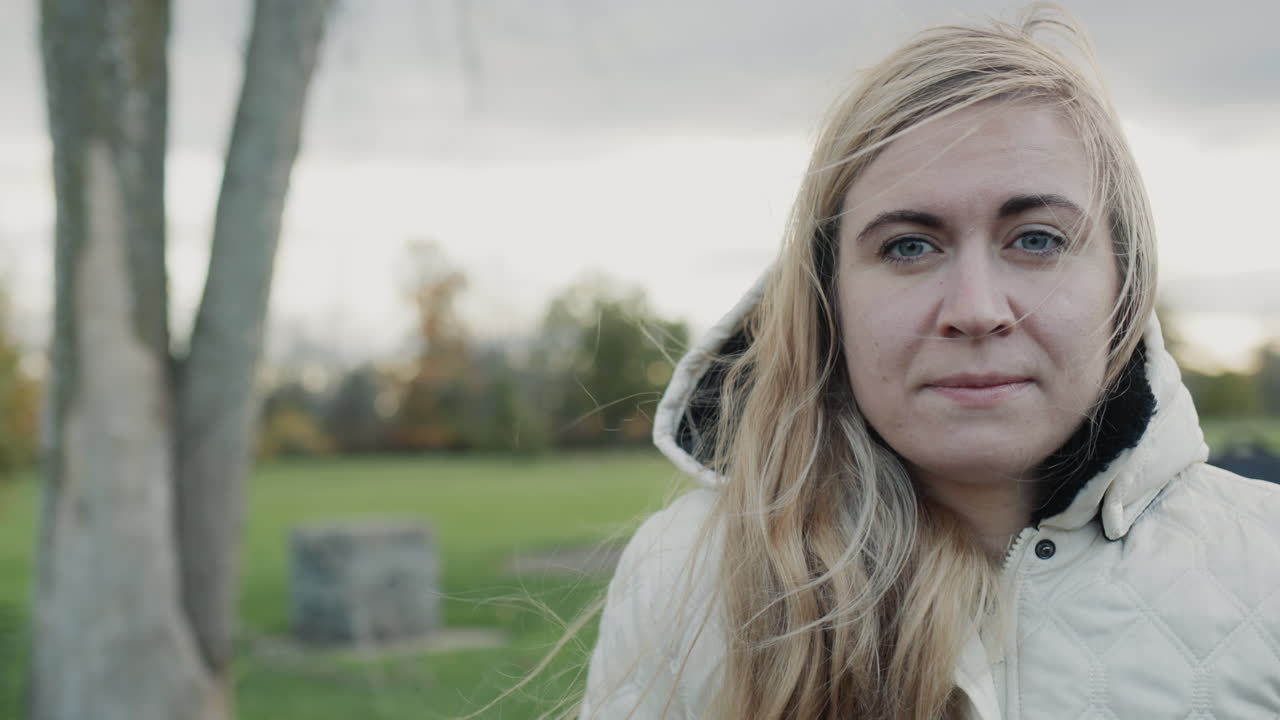 가을 공원 에 있는 젊은 사려 깊은 여자 의 초상화. 머리 에 후드 를 쓴 재 ⁇  을 입고 서 있다