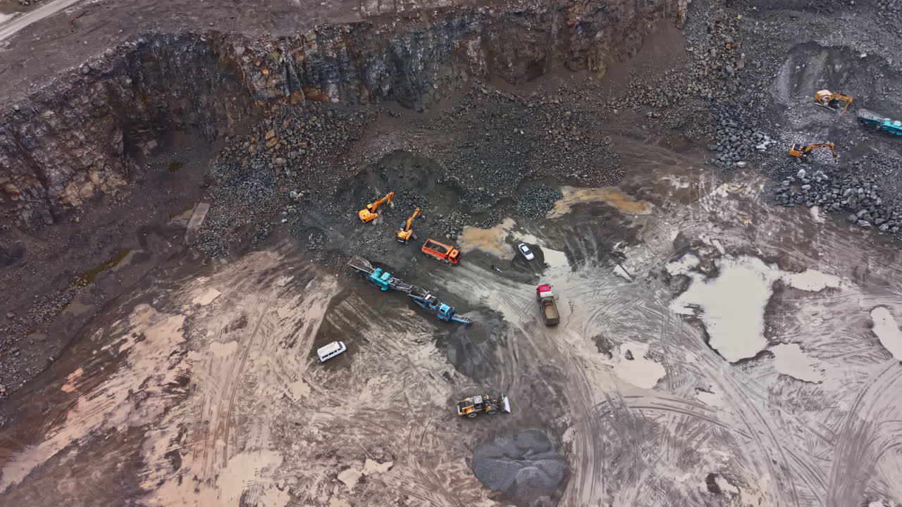 Granite quarry work site showing machinery and extraction process in action during daylight hours in a large open pit