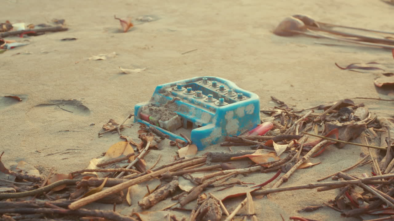 Inquadratura statica di rifiuti di plastica abbandonati tra legni sulla spiaggia