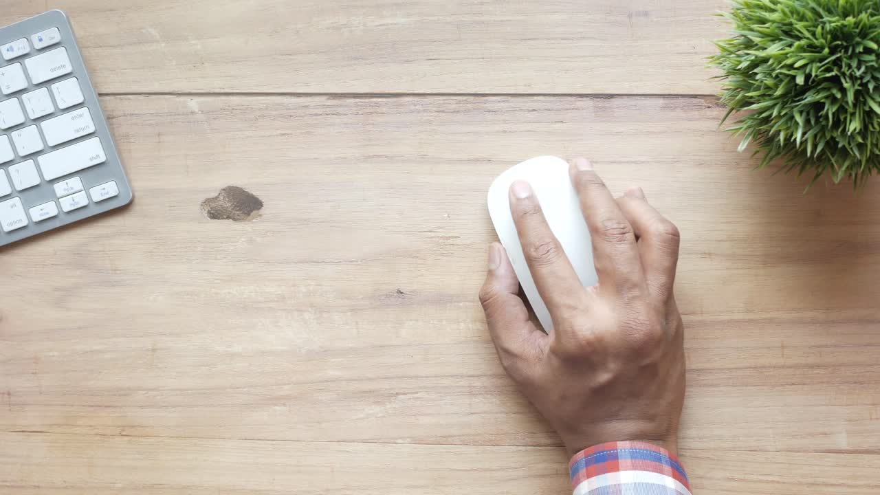 persona usando un ratón de computadora en un escritorio de madera