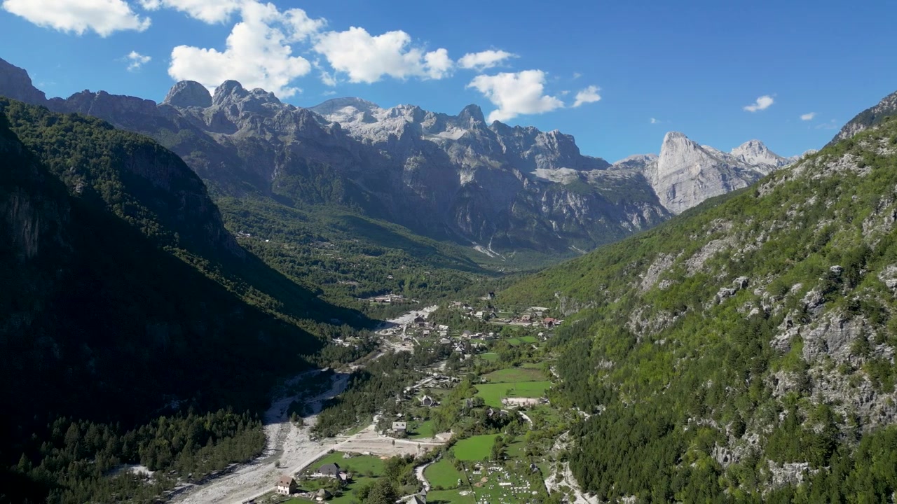 Una vista aerea mozzafiato delle Alpi Albanesi e dei tradizionali villaggi di montagna, che mostra cime spettacolari, valli lussureggianti e la bellezza naturale incontaminata dell'Albania settentrionale. Ideale per viaggi e turismo