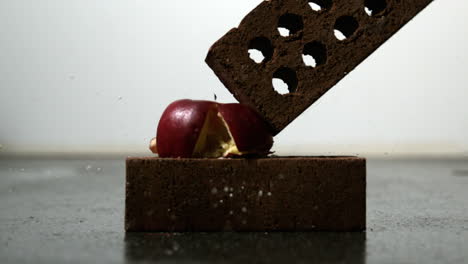 apple being squashed between two bricks