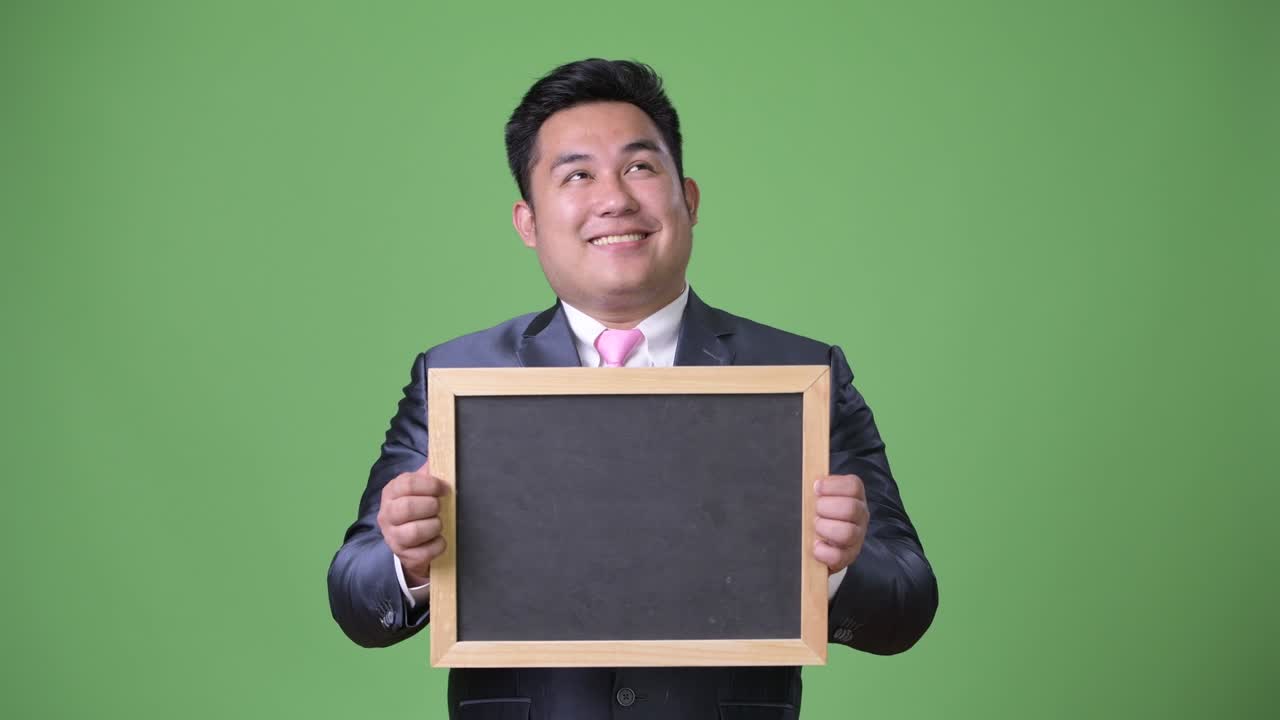 초록색 배경에 젊은 잘생긴 과체중 아시아 사업가