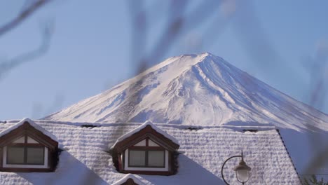 Incredible-view-over-snow-capped-top-of-Mount-Fuji-behind-house-roof-in-Japan