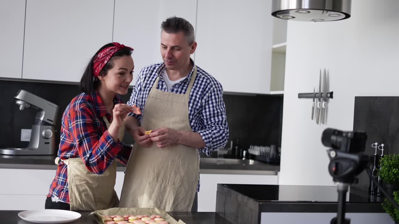 pareja adulta en la cocina horneando en casa, hablando en la cámara y probando galletas