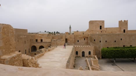 view inside of ancient fortress ribat of monastir with trees and walking tourists, tunisia