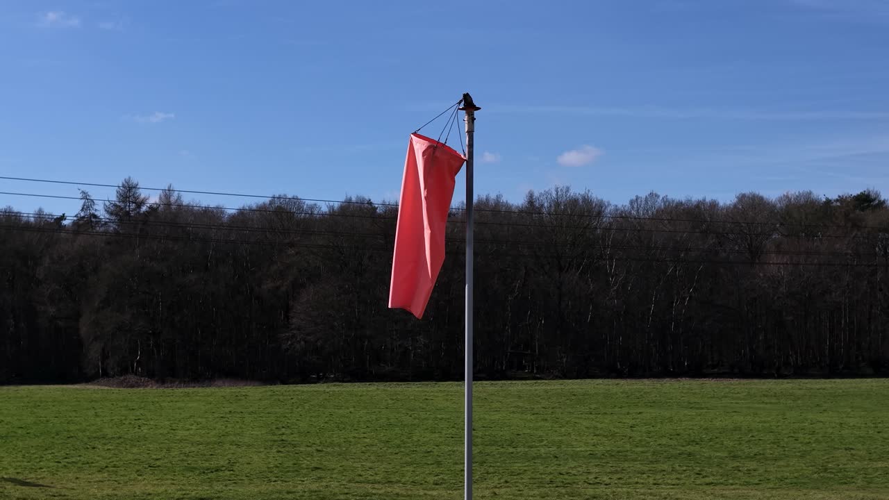 Flag blowing in the wind against a blue sky and green field background
