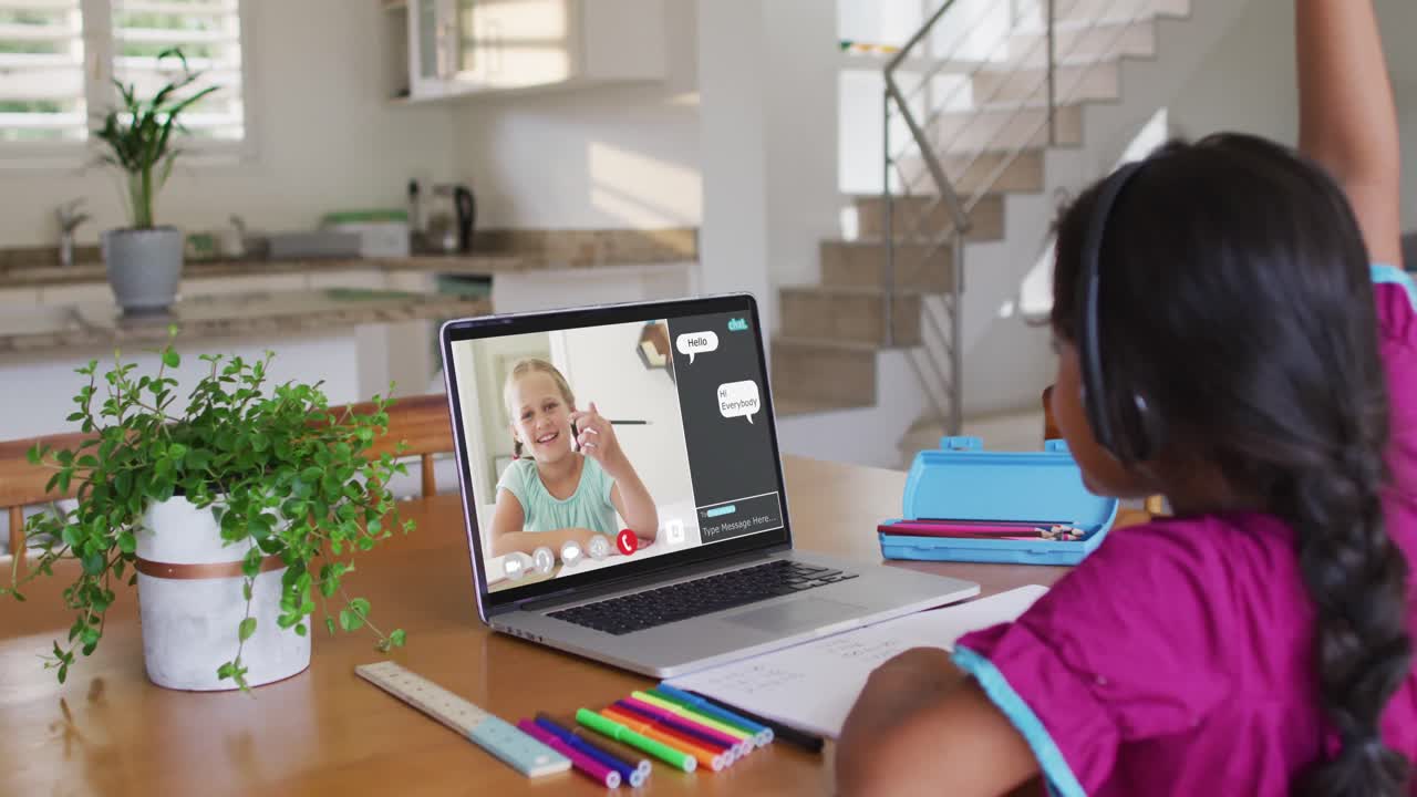 Schoolgirl using laptop for online lesson at home, with her colleague and web chat on screen