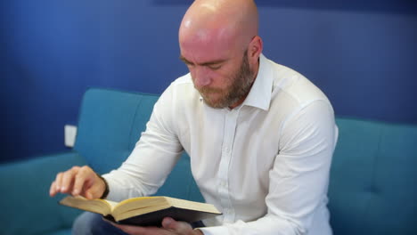un hombre sosteniendo y leyendo un libro con los dedos siguiendo las líneas