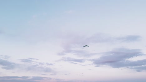 A-solitary-paraglider-gracefully-navigates-the-expansive-skies-above-Utah,-USA,-gliding-serenely-over-the-rugged-and-arid-terrain,-symbolizing-freedom-amidst-the-expanse-of-the-desert-landscape