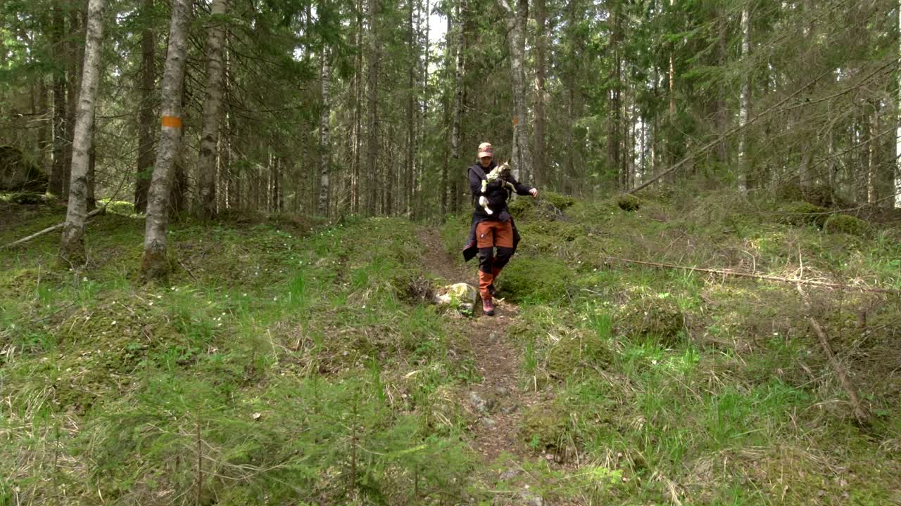 Female Hiker Carefully Carrying Dog at Hiking Trail in Forest, Slow Motion