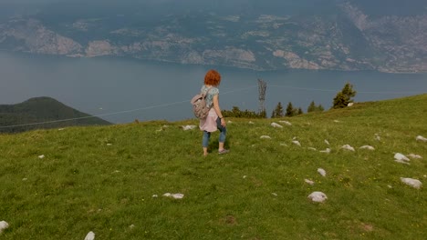 Luftaufnahme,-Die-Einer-Frau-Folgt,-Die-Auf-Einen-Berg-Geht-Und-Anhält,-Um-Die-Landschaft-Zu-Betrachten