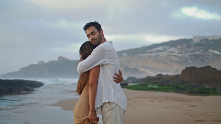 Homme amoureux portant sa femme dans un paysage marin. Beau couple profitant de la mer.