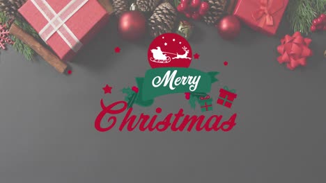 Animation-of-merry-christmas-text-banner-over-christmas-gifts-and-decorations-on-grey-surface