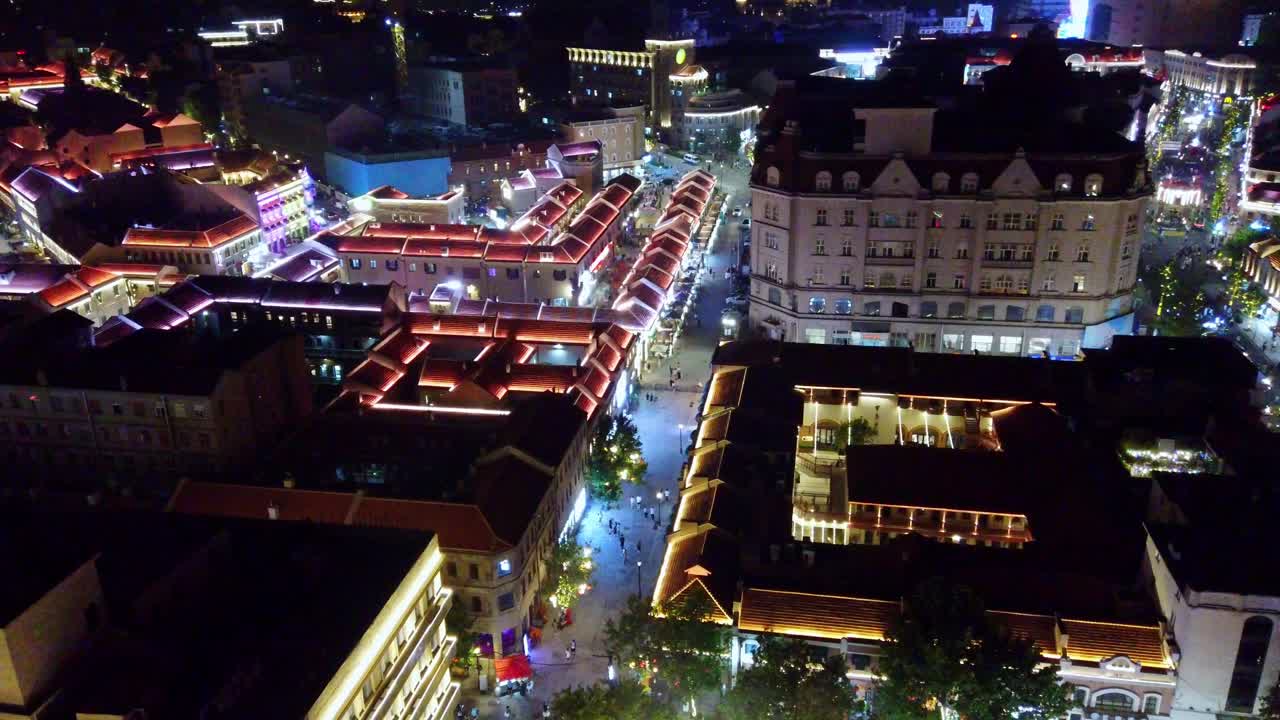 Night aerial view of a vibrant illuminated city street with historic architecture