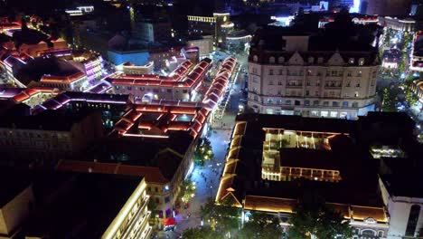 night aerial view of a vibrant illuminated city street with historic architecture