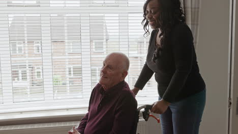 elderly man in wheelchair with caretaker at home