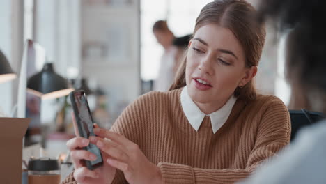 joven gerente de negocios usando un teléfono inteligente entrenando a un pasante apuntando a la pantalla compartiendo retroalimentación discutiendo ideas con un colega en la oficina