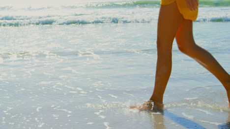 sección baja de la mujer caminando por la orilla de la playa 4k