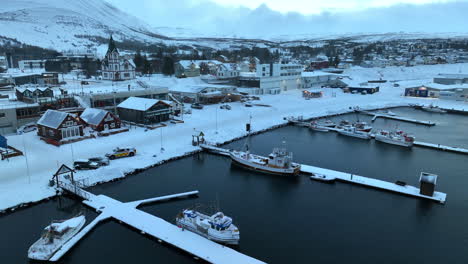 icelandic fishing boats moored at the jetties in the harbor in winter landscape of husavic