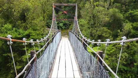 Slow-walk-across-swing-bridge-above-spectacular-river-gorge---Hokitika-River-Gorge-Walk,-West-Coast