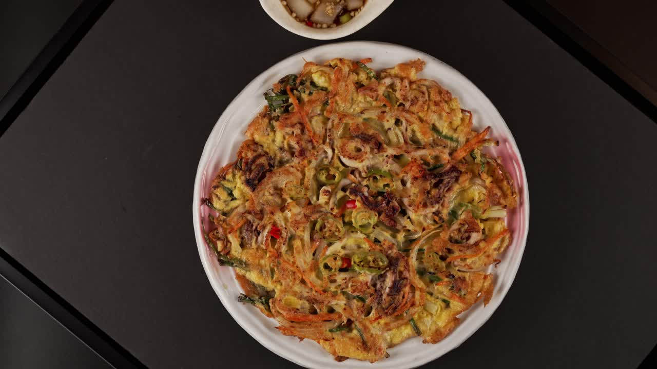 A crispy seafood scallion pancake with rich flavors, best paired with spicy soy sauce. 풍부한 맛을 지닌 바삭한 해물 파전이 매콤한 간장 소스와 가장 잘 어울립니다.