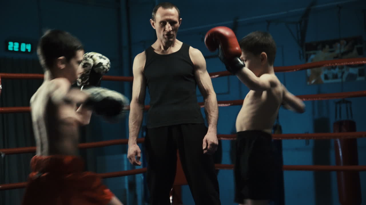 Young boys training Muay Thai with coach in a boxing ring