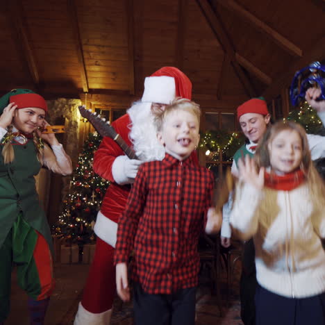 happy children with fairy characters dancing in christmas decorated room. christmas celebration with musical instruments inside the santa's residence.